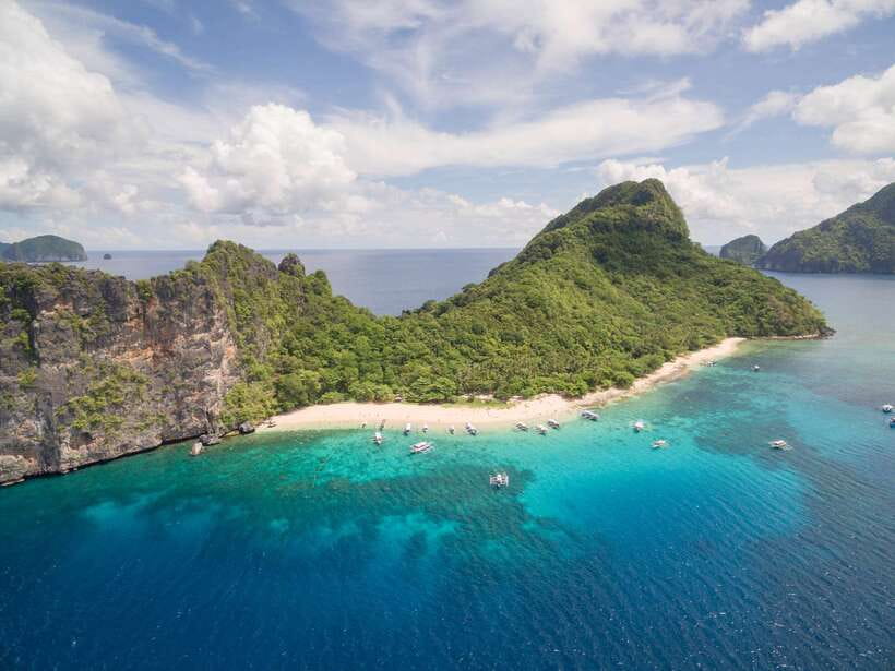 Outrigger bangkas moored under limestone cliffs in Bacuit Bay, El Nido